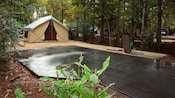 Terrain de camping comprenant un espace de stationnement en béton et un raccordement à l’égout pour un véhicule récréatif, ainsi qu’une aire de gravier avec une tente