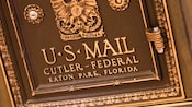 Front of a bronze U.S. Mail chute