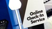 Un letrero, sobresaliendo de una pared, que dice 'Online Check-In Service' (Servicio de check-in en línea)