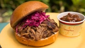 Pulled pork on a bun with red cabbage near a cup of chili