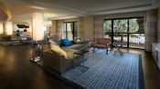 Un área de estar con un sofá, butaca, ventana, adyacente a un área de comedor y una sala de estar