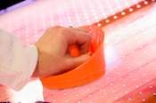 Close-up of a hand holding an orange air hockey paddle on the table