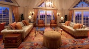 Una sala de estar con 3 sets de puertas de vidrio, 2 sofás, 2 mesas ratonas y 2 sillas