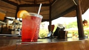 Une boisson qui contient une cerise et un quartier d'orange est placée sur le bar