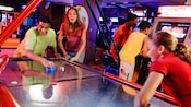2 adolescents jouant au hockey sur coussin d’air dans la salle d'arcade d’un hôtel Disney