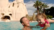 A father gleefully playing with his daughter in the Sandcastle Pool at Disney’s Old Key West Resort
