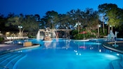 An illuminated swimming pool featuring an ornate fountain glimmering beneath a moonlit Florida sky