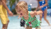 Espirros d'água com uma jovem visitante aproveitando a área da piscina no Disney's Port Orleans Resort