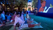 A man and his son are among the families watching The Princess and the Frog on a lawn at night