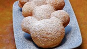 Beignets shaped like Mickey Mouse topped with powdered sugar