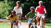 Une famille de 4 portant des casques et faisant du vélo sur une piste boisée