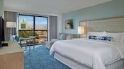 Une chambre à l’hôtel Swan de Walt Disney World comprend un très grand lit, un ameublement contemporain et une vue