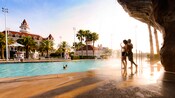 A man and a woman enjoy the Beach Pool’s waterfall at Disney’s Grand Floridian Resort & Spa