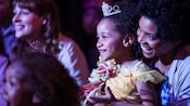 Uma garota sorridente usando uma roupa de Princesa da Disney sentada no colo da mãe