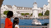 A woman and child gaze at the lake in front of Disney's Yacht Club Resort
