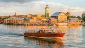 A small ship sails along the water in front of The BOATHOUSE at Disney Springs