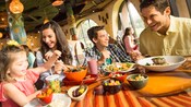 A smiling family sits at a table set with food