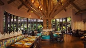 Dining area at Boma—Flavors of Africa, featuring a thatched ceiling and panoramic windows with a garden view