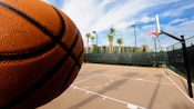 Close-up perspective of a basketball in front of a basketball court