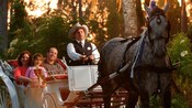 Un hombre con sombrero de vaquero pasea 3 a una familia de  personas en un carruaje tirado por caballos