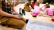 Un empleado de Disney sostiene un pelícano de felpa mientras otro miembro del elenco interactúa con 3 niños