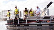 Debout sur un bateau ponton, des visiteurs mettent leur canne à l’eau tout près du Disney’s Contemporary Resort 