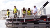 Debout sur un bateau ponton, des visiteurs mettent leur canne à l’eau tout près du Disney’s Contemporary Resort
