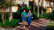 Um homem e uma mulher fazendo cooper por um caminho de um Hotel Resort Disney.