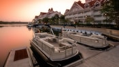 2 boats moored at a dock alongside the grounds of a Disney Resort hotel