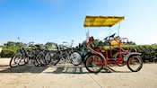 Um bicicletário com 6 bicicletas e uma bicicleta de quatro rodas