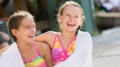 Two laughing young Guests in swimwear are wrapped in a towel together