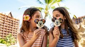 2 girls outside Aulani, A Disney Resort and Spa enjoy a Mickey Mouse ice cream bar