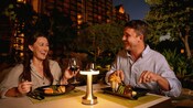 Two Guests enjoying dinner together at &lsquo;AMA&lsquo;AMA in Aulani, A Disney Resort & Spa