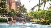 A family swimming in the Aulani resort pool