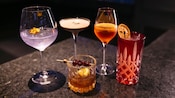 Una mesa con cinco bebidas mezcladas sin alcohol en vasos variados