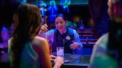 A Cast Member mixing a drink for 2 Guests at the bar of the Haunted Mansion Parlor on the Disney Treasure