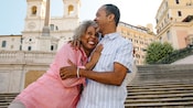 A man and a woman smile while hugging each other on the Spanish Steps in Rome, Italy
