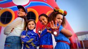 Cuatro niñas vestidas con trajes de heroínas de Marvel posan cerca de un embudo de un barco de Disney Cruise Line