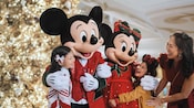 Mickey Mouse y Minnie Mouse saludan a una madre y a dos niñas junto a un árbol de Navidad en un barco de Disney Cruise Line Mickey Mouse y Minnie Mouse saludan a una madre y a dos niñas junto a un árbol de Navidad en un barco de Disney Cruise Line