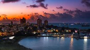 Horizonte de Colón, Panamá durante el atardecer con edificios iluminados y barcos anclados en alta mar.