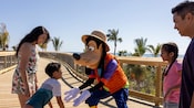 Goofy in a Junkanoo outfit high fiving a child next to the rest of the family on a boardwalk in The Bahamas
