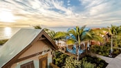 Una hilera de cabañas y palmeras al atardecer en Disney Lookout Cay en Lighthouse Point