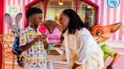 Mãe e filho sorrindo e segurando um sorvete ao lado das estátuas de Judy Hopps e Nick Wilde na sorveteria Jumbeaux's Sweets, no Disney Treasure