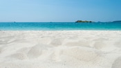 A beach along a shoreline in Langkawi with clear water and a small island in the distance