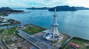 The Maha Tower rising from the coastline, overlooking a bay dotted with boats and distant forested islands