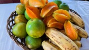 Starfruit, limes, bananas and other fruit in a wicker basket, set on a table