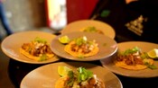 A server carrying plates with tacos on them