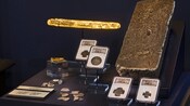 An exhibit at the Pirates Treasure Museum in Saint Thomas featuring a silver ingot, a gold bar, coins and metal fragments