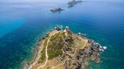 A rocky island with a stone tower surrounded by the Mediterranean Sea