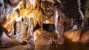 The interior of an illuminated cave with a metal walkway with railings 